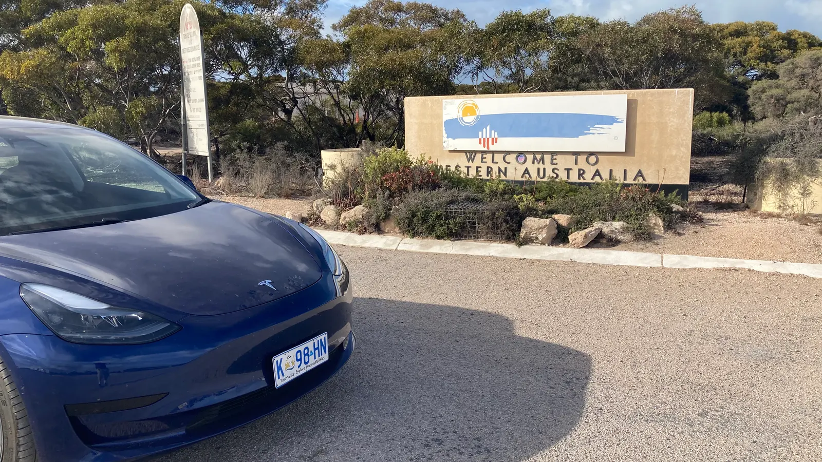 Driver holding an overseas licence beside a rental vehicle